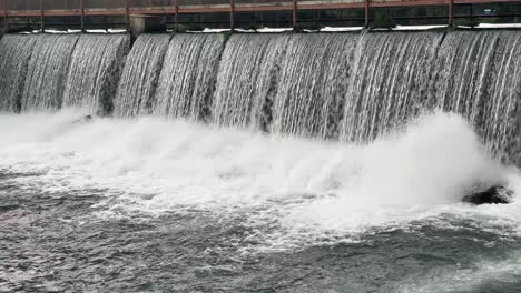 cascada de una presa que salpica sobre las rocas causando niebla