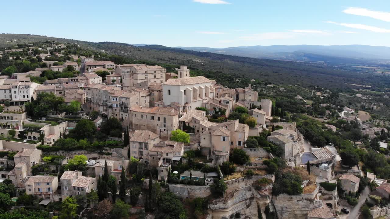 un dron vuela alrededor de gordes revelando el valle abierto detrás del pueblo