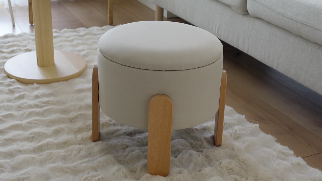 A modern upholstered ottoman on a fluffy rug in a living room setting