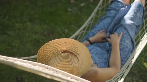 woman-wearing-a-straw-hat-swings-in-a-hammock