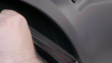 trimming excess car wrapping foil around wheel well with knife, static