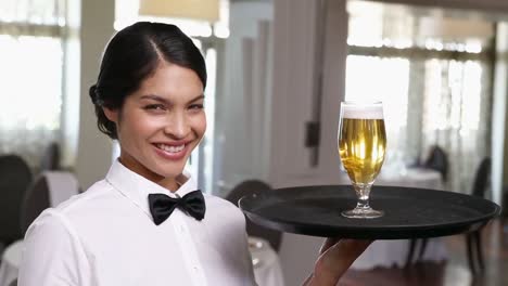 Pretty-waitress-holding-tray-with-glass-of-beer