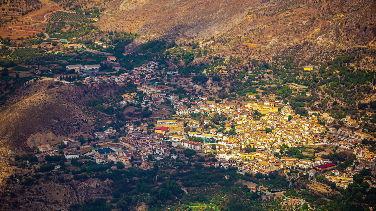 una toma aérea de nubes sombras moviéndose a través de un paisaje urbano rodeado de montañas