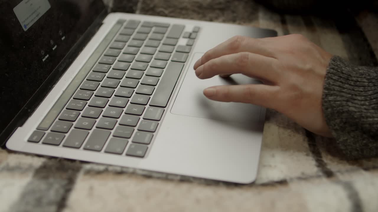 la mano de un hombre tratando de solucionar un problema en una computadora usando un trackpad y un teclado