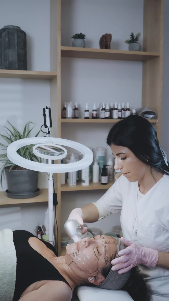 Estetista che esegue un trattamento viso su una cliente in una clinica estetica