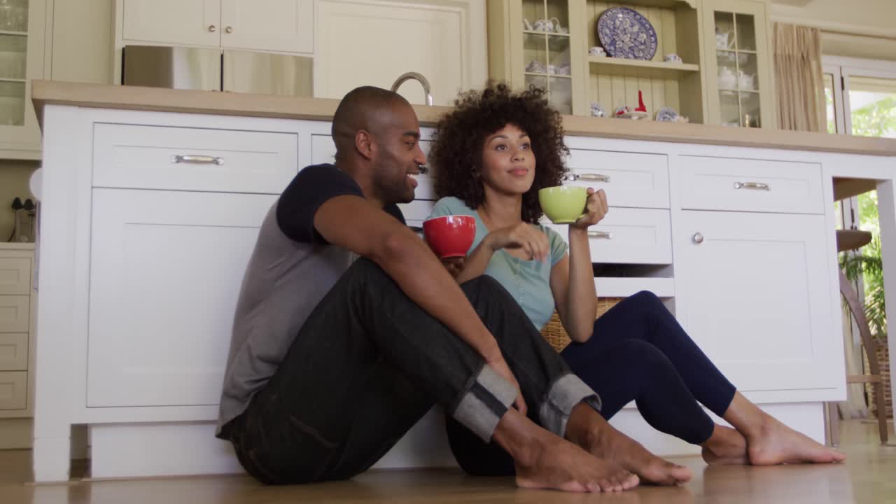 Happy mixed race couple drinking coffee in their kitchen