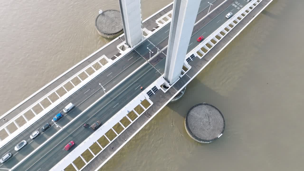 Vehicle traffic crossing the Jacques Chaban Delmas lift bridge over the Garonne River in Bordeaux France to Bassins &agrave; flots neighborhood , Aerial looking down tilt up shot