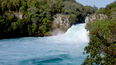 Personas-Diminutas-En-La-Distancia-En-Una-Plataforma-De-Observación-Disfrutando-Viendo-La-Cascada-Gigante-De-Huka-Falls-En-Un-Día-En-Taupo,-Nueva-Zelanda-Aotearoa