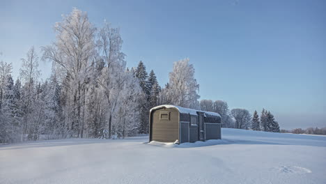 Statische-Aufnahme-Einer-Hölzernen-Ferienhütte,-Die-Während-Der-Wintersaison-Den-Ganzen-Tag-über-Mit-Einer-Dicken-Schicht-Weißen-Schnees-Bedeckt-Ist,-Im-Zeitraffer-Mit-Bäumen-Im-Hintergrund