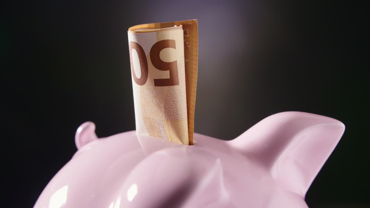 Sparschwein mit 50-Euro-Schein dreht sich auf dem Tisch