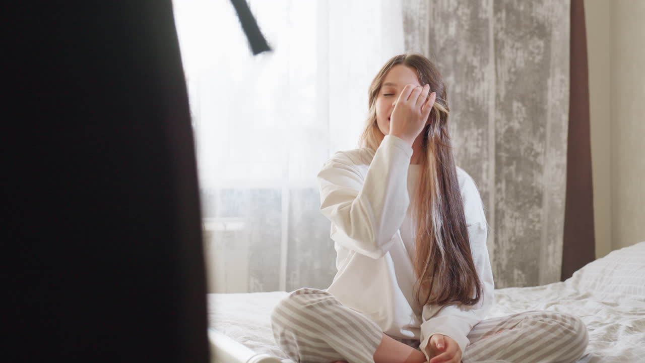 School roommate in striped night wear seated on bed applauds and praises bestie dress sense with booming smile, natural daylight filling cosy bedroom highlighting supportive friendship moment