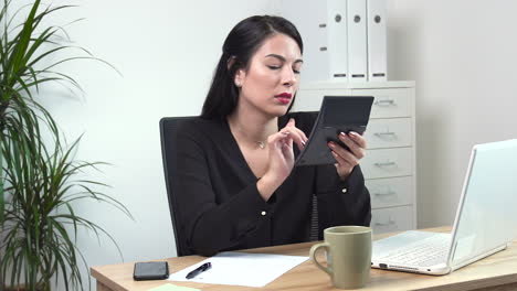 Atractive-Female-office-worker-calculating-at-desk-sad