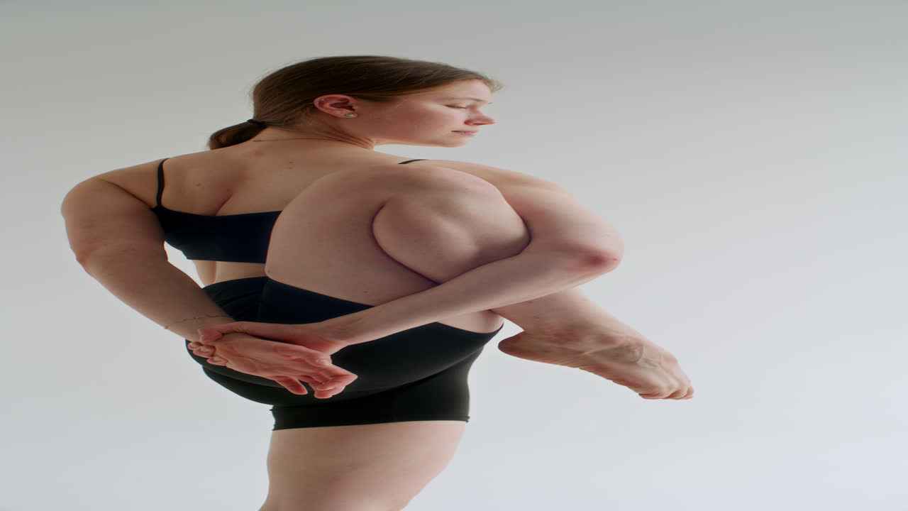 Young Woman Balancing in Yoga Pose against White Background