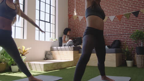 Mujeres-De-Negocios-Jóvenes-Practican-Meditación-De-Yoga-Juntas-En-La-Oficina-Haciendo-Pose-De-Guerrero-Disfrutando-Del-Ejercicio-De-Atención-Plena-Relajándose-Durante-El-Almuerzo