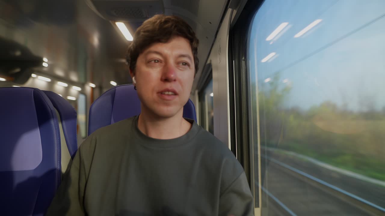 Man traveling by train, using smartphone and earbuds