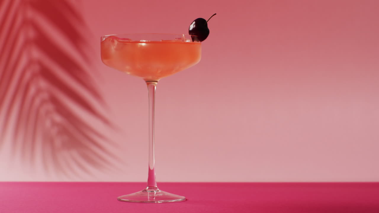 Primo piano di bevanda con ciliegia su sfondo rosa