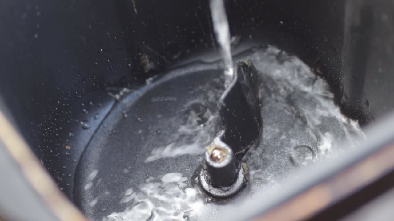 Pouring water into a bread machine close up shot
