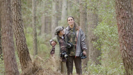 Mother-and-son-in-a-natural-park-posing-and-looking-at-camera,-then-kissing-each-other-on-cheek