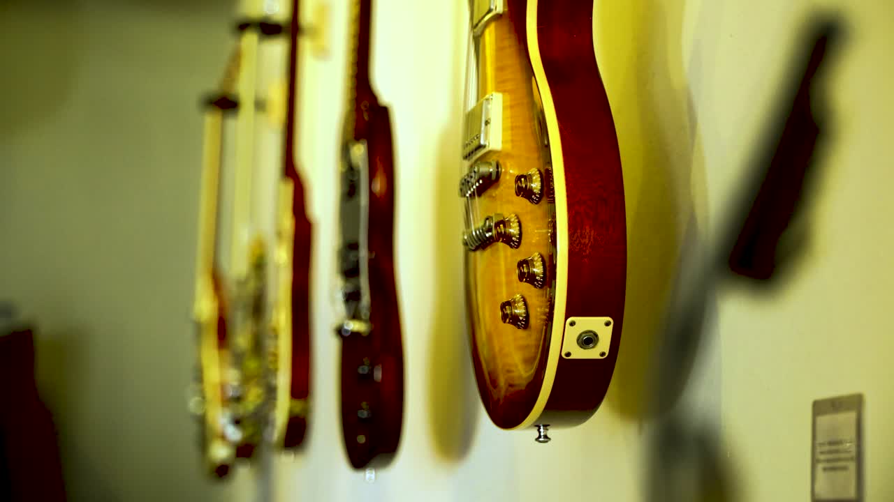 Five classic guitars adorn the wall as a collector's showcase, with a shift in focus from the foreground to the background