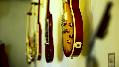 five classic guitars adorn the wall as a collector's showcase, with a shift in focus from the foreground to the background