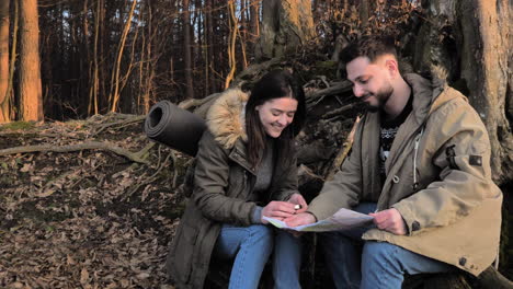 una pareja caucásica revisando el mapa en un bosque.