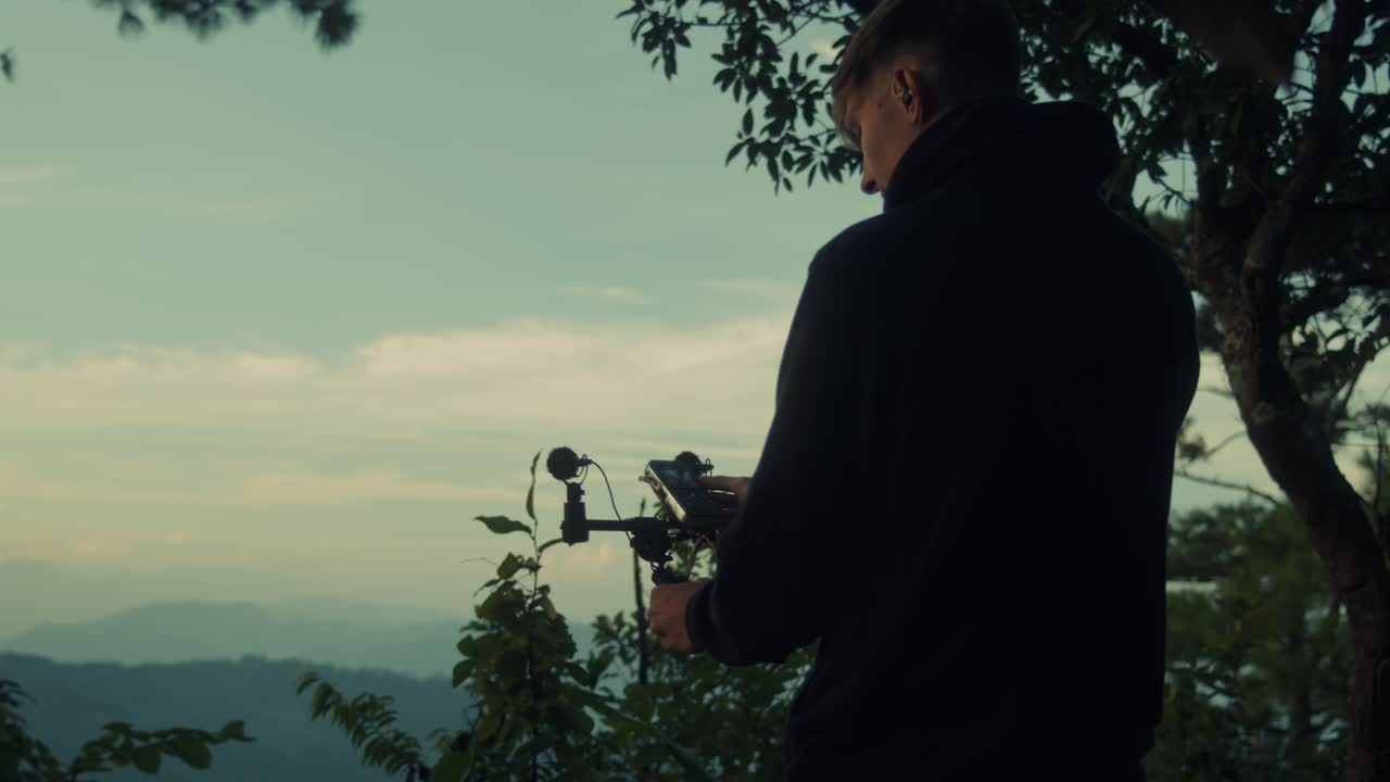 Videographer recording a video in the mountains at sunset
