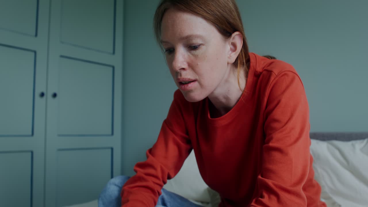 женщина сидит на кровати и смотрит на ноутбук.