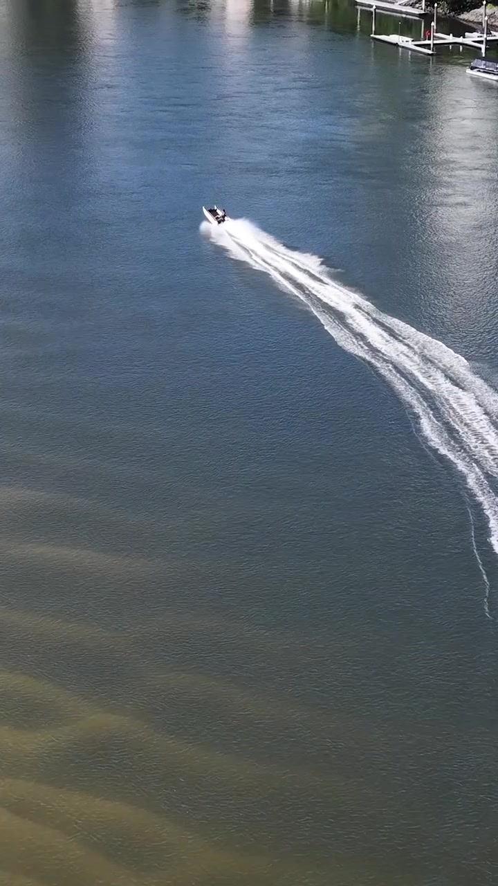 Ripresa aerea con drone di un motoscafo che lascia una scia bianca su un canale.