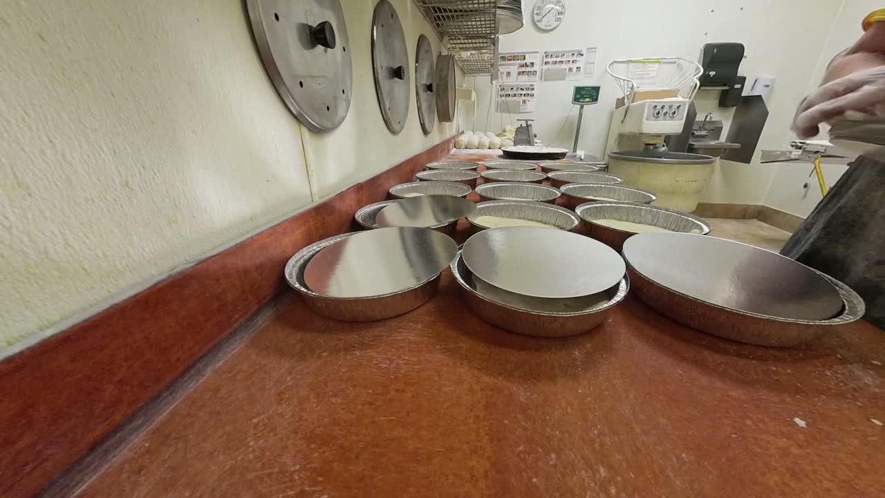 Worker puts lids on pizza aluminum foil bins