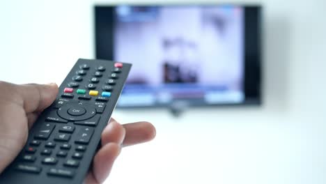 hand holding a tv remote control in front of a tv screen