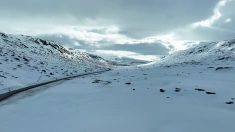 road rv 15 crossing sstrynefjellet through breiddalen in norway - forward and ascending aerial revealing road disappearing into vast mountain landscape