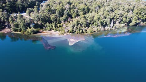 River-pouring-muddy-water-into-blue-lake,-aerial-view