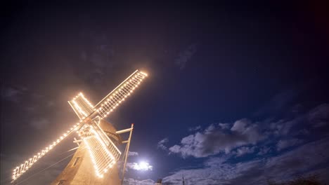 windmill illuminated in lights under a full moon evening in ameland, netherlands - low-angle night shot