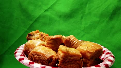 4k loop2-3 rotating plate of baklava on an appetizer plate with a green screen background and all the desserts vary in squares, rolls with pistachio inside and glazed with rose water sugar to reflect