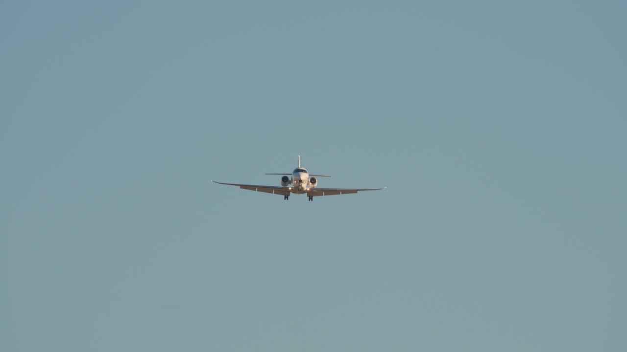 Jet privato bianco in fase di atterraggio con cielo blu limpido sullo sfondo