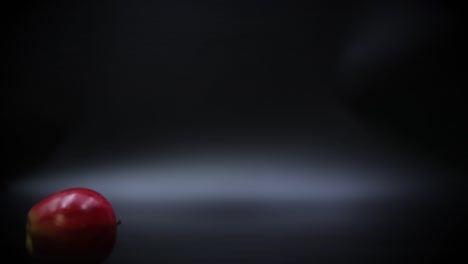 Slow-Motion-Hand-Spinning-a-Ripe-Red-Apple-on-a-Black-Surface