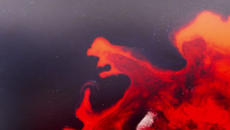 swirling red alcoholic ink forms abstract patterns in macro with a cosmic feel