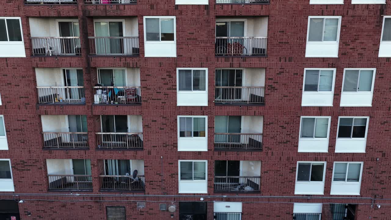 Nært luftfoto af et lejlighedstårn i mursten i USA, der viser gentagne altaner og vinduer. Udvendig urban beboelsesejendom, der fremhæver moderne byboligarkitektur.