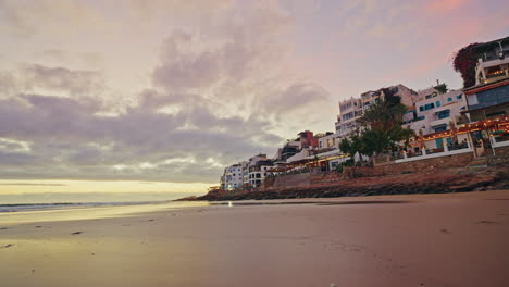 taghazout bay in morocco at sunset. view of beach, the local town. golden hour, warm sky with fluffy clouds. slow motion