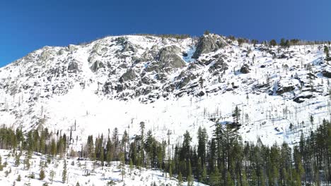 Aerial-view-of-tall-rocky-mountains-and-forested-wilderness,-Twin-Pines,-California,-Horsetail-Falls