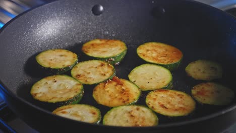 fork used in flipping slices of zucchini frying in a pan