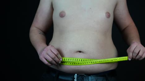 overweight man measuring his belly, close up