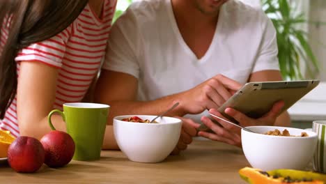 Happy-couple-using-tablet-and-having-breakfast