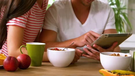 happy couple using tablet and having breakfast