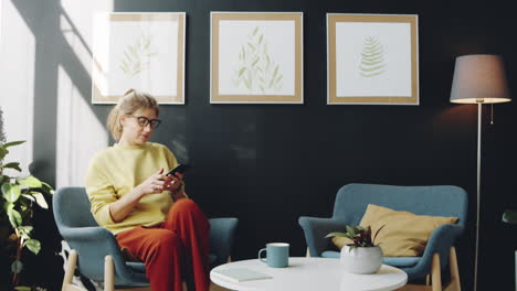 Mujer-Usando-Teléfono-Inteligente-Y-Tomando-Café-En-Casa