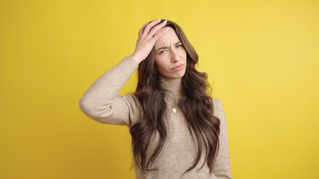Young woman suffering from headache on yellow background