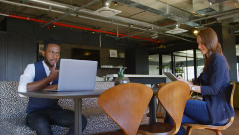 young cool mixed-race business executives using multimedia devices in cafeteria of modern office 4k