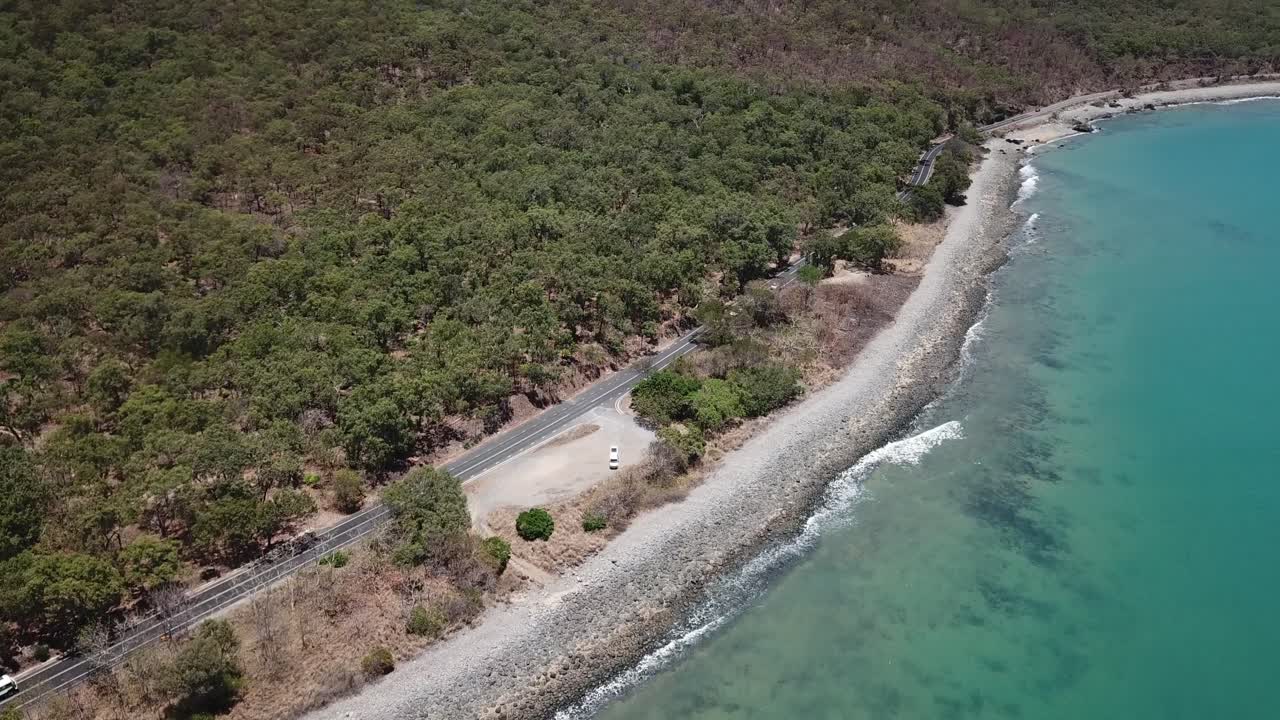 Drone pan up over tropical beach to green mountain
