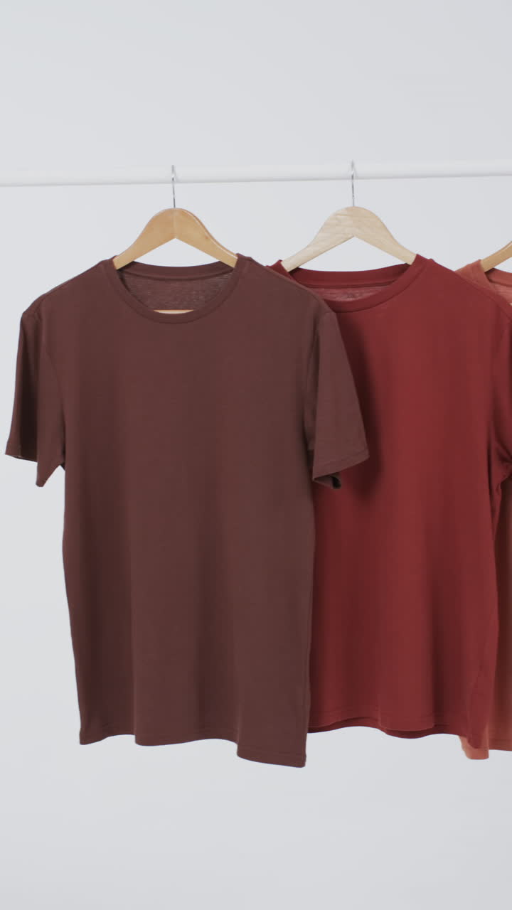 Vertical video of brown t shirts on hangers and copy space on white background