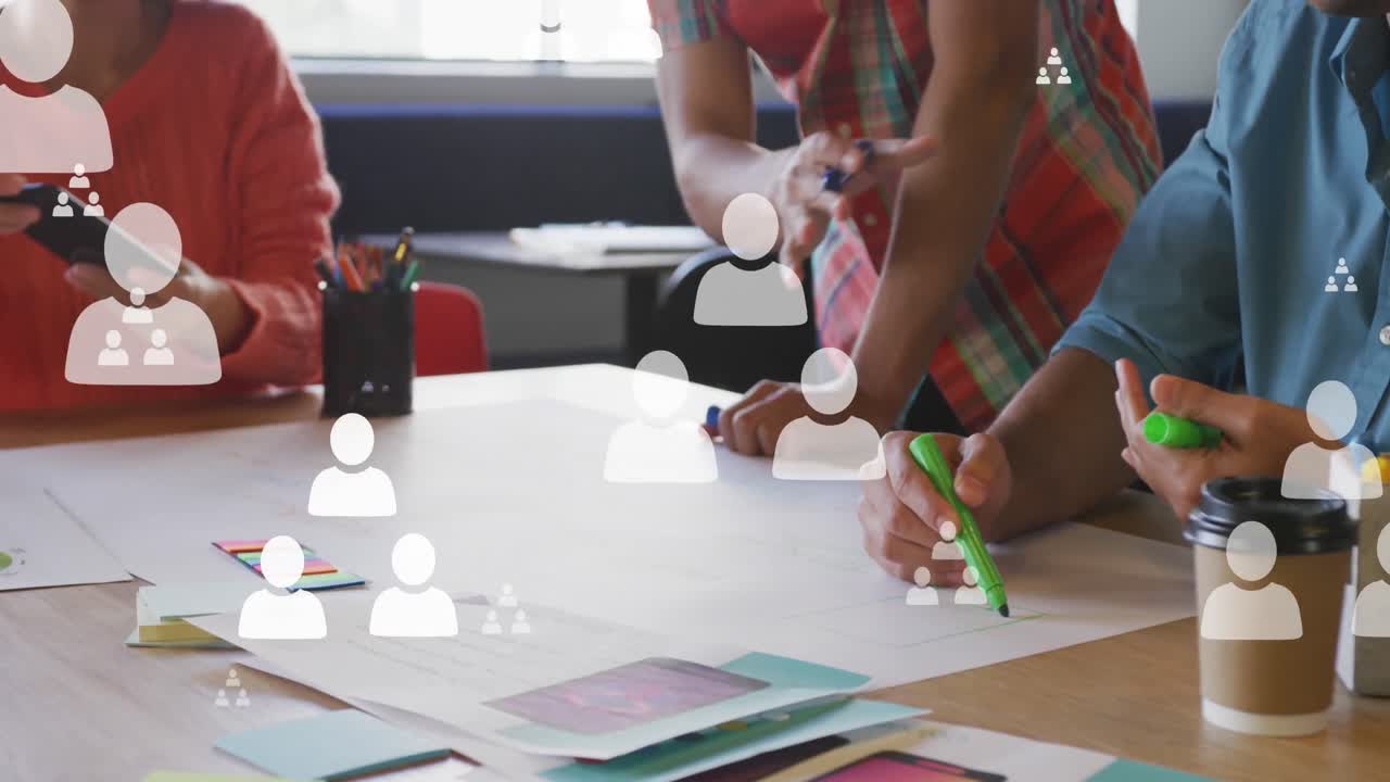 Animation of profile icons floating over mid section of colleagues discussing over a plan at office